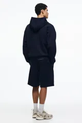 Short de felpa interlock color negro, de corte relajado a la rodilla, con cintura elástica con cordón ajustable oculto y bolsillos laterales.