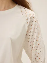 Remera de algodón con escote a la base y mangas raglán de broderie con costuras decorativas en color contrastante.