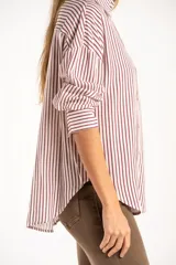 Camisa de corte oversize con estampado de rayas verticales, cuello clásico, cierre frontal con botones y bolsillo en el pecho. Presenta mangas largas con puños abotonados y un diseño fluido.
