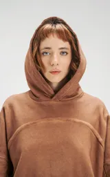 Hoodie oversize color beige con efecto batik, costuras expuestas y recortes estructurales. Presenta capucha amplia y bolsillo frontal tipo canguro.