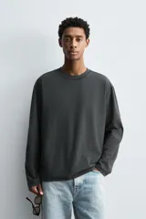 Camiseta relaxed fit de manga larga color gris oscuro, confeccionada en tejido compacto de algodón. Presenta cuello redondo y costuras con efecto revés.