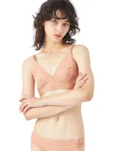 Brasier triangular de encaje color salmón, con breteles regulables y banda inferior elástica con logo Calvin Klein.