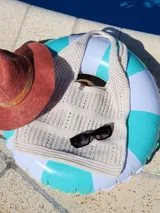 Bolso tejido en hilo color crudo, con diseño calado y asas anchas.