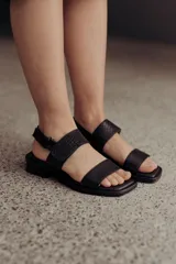 Sandalia Roma de cuero dorado, con tiras anchas, una lisa en la puntera y otra con textura reptil en el empeine, y tira ajustable al talón con hebilla. Suela plana y cómoda.