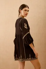 Vestido corto de viscosa crepe color negro, con escote en V, mangas largas abullonadas y detalles de bordado en hilo a contratono en el escote, mangas y ruedo.