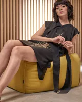 Vestido corto negro con estampado abstracto en amarillo, escote en V cruzado y lazo en la cintura.