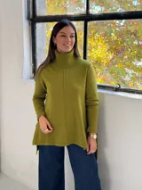 Sweater de punto color verde pistacho, con cuello alto tipo polera, mangas largas y diseño holgado con costuras verticales decorativas.