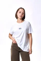 Remera blanca de algodón con cuello redondo y estampado pequeño en el pecho con la bandera de Uruguay.