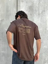 Remera marrón de corte amplio con estampado en la espalda con la palabra 'Perception' y otras frases en color dorado.