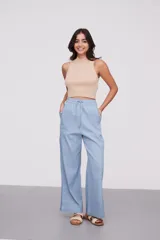 Pantalón celeste de algodón, de tiro alto y corte ancho, con cintura elástica ajustable mediante cordón y aberturas laterales en los bajos.
