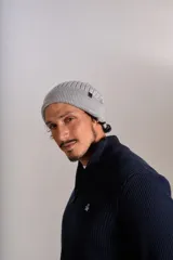 Gorro tipo beanie de tejido acanalado en color gris, con etiqueta pequeña con logo en el lateral.
