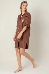 Vestido camisero corto de lino color celeste, con cuello clásico, cierre frontal con botones, mangas 3/4 con trabillas y bolsillo de parche en el pecho con bordado de iniciales.