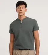 Remera masculina slim fit color verde oscuro, confeccionada en algodón peruano. Presenta cuello padre y abertura frontal con cremallera metálica, mangas cortas y tejido de algodón certificado Bci.
