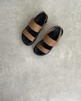 Sandalia negra de plataforma gruesa, con dos tiras anchas sobre el empeine y tira ajustable en el talón.