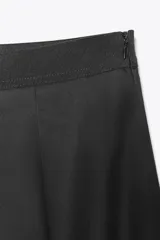 Falda midi de tiro medio en color negro, confeccionada en algodón. Presenta un diseño con pliegues verticales y cierre lateral con cremallera oculta.