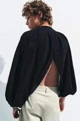 Top corto negro de punto fino, con cuello redondo y mangas largas abullonadas con pliegues.