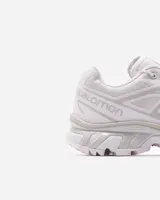 Championes Salomon modelo XT-6, color blanco con detalles sutiles en gris y acentos multicolor en el sistema de cordones. Diseñados para trail running, cuentan con una estructura resistente, suela con agarre técnico y sistema de ajuste rápido.