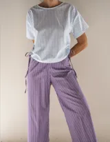 Pijama de algodón a rayas, compuesto por una remera de manga corta con cordones ajustables en los laterales y un pantalón de corte recto y holgado.