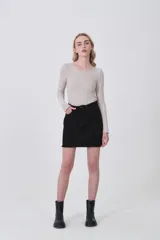 Falda mini de jean color blanco con costuras en contraste color ocre. Presenta un detalle de trenzado decorativo en los bolsillos delanteros y ruedo desflecado.