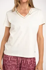 Remera de algodón peinado color blanco, con escote en V y detalles de lurex dorado en el borde del escote. De manga corta y corte ajustado.