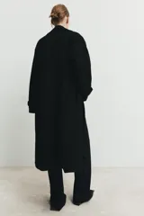 Abrigo largo de corte oversize con cuello de solapa, manga larga y cierre frontal cruzado con botones. Cuenta con bolsillos delanteros.