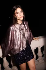 Camisa metalizada color rosa, de seda ligera, corte holgado, hombros caídos y mangas cortas.