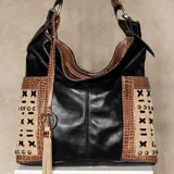 Cartera negra de cuero vacuno con detalles en cuero con textura de cocodrilo color tostado y beige. Tiene dos bolsillos laterales y un bolsillo trasero con cierre. Incluye correa extensible y removible para usar como morral.