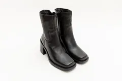 Bota de caña media color negro, de cuero, con punta cuadrada y taco bloque.