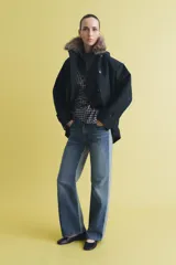Trench corto de corte recto con capucha y cuello desmontable efecto pelo. Presenta cierre frontal con botones, bolsillos laterales y mangas largas con trabillas en los puños.