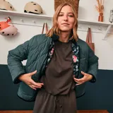 Chaqueta corta con estampado floral en tonos rosa y celeste sobre fondo negro. Tiene cuello mao y cierre frontal con botones a presión.
