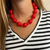 Collar corto de cuentas grandes color rojo brillante. Las cuentas son esféricas y de diferentes tamaños.