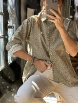 Camisa de pana elastizada color verde militar con estampado flocado en tono claro, manga larga con presilla para arremangar, cuello camisero y cierre frontal de botones.