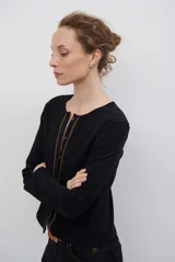 Cardigan negro de algodón con cuello redondo, cierre frontal de botones y costuras en contraste color ocre.