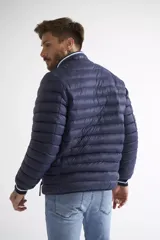 Campera puffer de nylon color azul marino, con cierre frontal completo, cuello alto y puños con detalle de rayas. Cuenta con bolsillos laterales con cierre y logo estampado en el pecho.