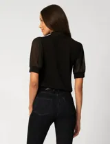 Blusa de color blanco con escote en V y detalle de lazo frontal. Presenta mangas cortas de gasa con terminación en puño.