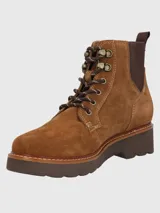 Bota acordonada de gamuza color marrón, con suela de plataforma dentada y paneles laterales elásticos. Presenta ojales metálicos y cordones bicolor.