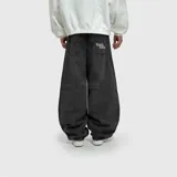 Pantalón de jean estilo ultra baggy, color negro con efecto lavado. Presenta un corte extremadamente holgado, bolsillos traseros con bordado de marca en tipografía gótica y costuras reforzadas.