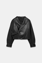 Chaqueta corta de piel 100% color negro, de estilo cruzado con cierre de hebilla lateral. Cuenta con cuello solapa ancho, manga larga con puños estructurados y forro interior.