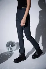 Pantalon de jean engomado color gris oscuro, de corte slim fit y tiro alto. Presenta costuras verticales frontales y aberturas en el ruedo.