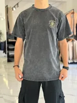 Remera oversize color negro con efecto gastado (acid wash), manga corta, y gran estampado en la espalda de una calavera con la inscripción "Mushkana Born to Chill".