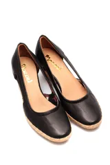 Zapato de taco corrido tipo cuña, confeccionado en cuero negro con aberturas laterales. Presenta una base de corcho y detalle de yute en la puntera.