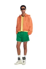 Sudadera cropped fit con capucha y cierre frontal de cremallera, confeccionada en tejido de algodón en color naranja. Cuenta con bolsillos frontales tipo canguro y efecto lavado.