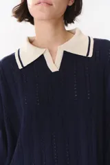 Sweater de punto color marrón con cuello polo en contraste color crema. Presenta diseño de rayas verticales texturizadas, mangas largas con puños en color crema y corte holgado.