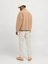 Pantalón cargo color beige de corte relajado, con cierre de gancho y cremallera, bolsillos traseros, frontales y laterales, tiro medio y detalle de cordones en los dobladillos.