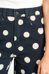 Jean de corte baggy y tiro alto, confeccionado en denim azul marino con estampado de lunares blancos, estilo barrel.
