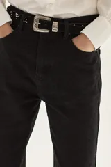 Cinturón de cuero gamuzado color camel, con diseño de tachas metálicas plateadas dispuestas en grupos triangulares y hebilla metálica labrada de estilo western.