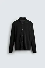 Sobrecamisa de punto negro de corte relajado, con cuello solapa y manga larga. Presenta cierre frontal de botonadura y acabados en rib.
