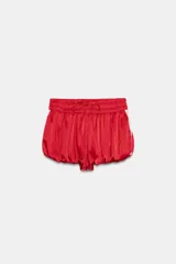 Shorts de tiro medio confeccionados en satén rojo, con diseño tipo globo y cintura elástica ajustable mediante cordones. Presentan detalles de encaje blanco en los laterales.