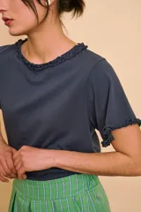 Remera gris oscuro de manga corta, con cuello redondo y terminaciones con volados fruncidos en el cuello y las mangas.
