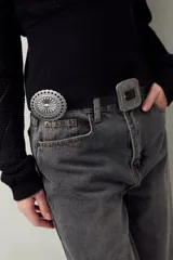 Cinturón negro de símil cuero con diseño western, apliques metálicos circulares y hebilla cuadrada grabada.